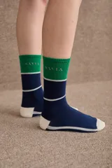 Medias de caña media con diseño tricolor en azul marino, verde y blanco. Presentan el logo de la marca bordado en la parte superior y detalles de líneas horizontales.