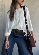Blusa oversize de color blanco con diseño romántico y bohemio, confeccionada con detalles de encaje y botones forrados en el frente. Cuenta con mangas largas.