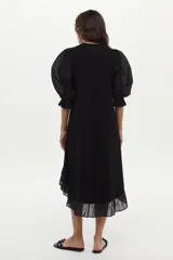 Vestido midi de corte recto color negro, con mangas cortas abullonadas, cuello redondo y detalle de volado en el ruedo.