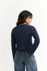 Sweater azul marino de punto trenzado, corte crop y mangas largas.