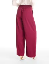 Pantalón tipo palazzo de corte ancho y fluido, confeccionado en tejido sastrero. Presenta tiro alto con doble abotonadura frontal, pinzas decorativas y cintura elástica en la parte posterior. Incluye bolsillos laterales funcionales.