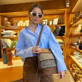 Bandolera de diseño tricolor con paneles en tonos marrón, beige y gris. Presenta múltiples cierres frontales, correa larga regulable y compartimento principal con cierre superior.