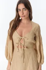 Vestido midi fucsia de lino, con escote en V, mangas largas abullonadas, lazos frontales y tajo lateral.