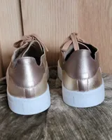 Zapatillas urbanas de cuero metalizado dorado y gamuza beige, con cordones anchos al tono y suela blanca.