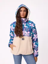 Campera tipo canguro con diseño combinado, parte superior estampada con flores en tonos azules y rosados, y parte inferior de tejido sherpa en color beige. Cuenta con cuello alto, cierre frontal parcial y bolsillo tipo canguro delantero con logo de la marca.