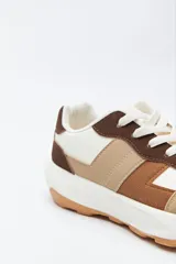 Zapatilla urbana de diseño contemporáneo con capellada que combina paneles de diferentes texturas en color negro, ajuste con cordones y suela robusta de color blanco.