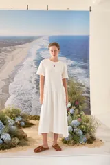 Vestido midi color crudo de manga corta, con corte en la cintura y falda holgada con volados y detalle de pequeño bordado de hongo en el pecho.