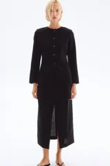 Blazer entallado negro en mezcla de lino y viscosa, con cuello redondo, hombreras finas, botones hasta la cintura y bolsillos delanteros de parche. Abertura en los puños y forro interno.