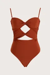Traje de baño enterizo color terracota con diseño strapless, detalle de nudos frontales y aberturas cut-out en el torso. Incluye breteles finos ajustables.