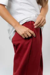 Pantalón jogger de calce relajado color bordó intenso, con cintura elastizada y lazo regulable. Cuenta con bolsillos laterales con cierre invisible y silueta recta levemente afinada.