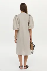 Vestido midi de lino color beige, con cuello mao, mangas abullonadas y cierre frontal de botones.
