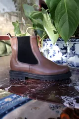 Bota de cuero color marrón, de caña media, con elásticos laterales negros, suela track y pequeño taco de 3 cm.