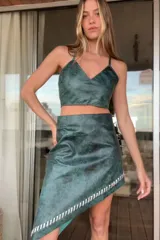Vestido corto verde con estampado abstracto, escote en V y falda asimétrica con detalle de pasamanería en cuero plateado.
