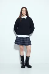 Sweater negro de tejido texturizado con líneas horizontales en relieve, de silueta levemente holgada y hombros caídos.