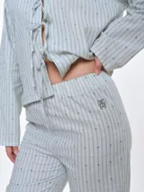Pantalón de dormir de corte recto y calce relajado, confeccionado en popelina de algodón con estampado de rayas verticales y pequeños puntos bordados. Presenta cintura elastizada para mayor comodidad.