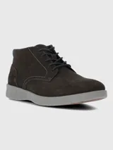 Bota urbana de caña baja confeccionada en cuero gamuzado color marrón oscuro, con cordones al tono y suela de poliuretano gris con tecnología de amortiguación.