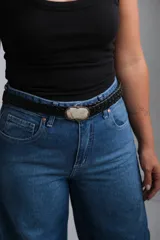 Cinto trenzado de cuero negro con hebilla central ovalada de piedra natural en tonos claros y borde metálico envejecido.