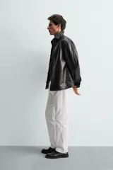 Sobrecamisa de corte regular confeccionada en piel napa negra, con cuello solapa, cierre frontal de botones y mangas largas con puños abotonados.