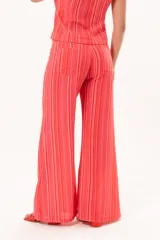 Pantalón de tiro medio y pierna amplia, con diseño a rayas en tonos rojos y rosados, bolsillos y pasacintos.