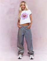 Remera blanca de algodón con estampado de una flor lila en el centro.