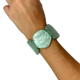 Pulsera elástica de resina color verde agua con piezas circulares y rectangulares.