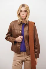 Chaqueta color camel con cuello camisero, cierre frontal con botones dorados, dos bolsillos de parche en el pecho y costuras decorativas en contraste.