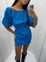 Vestido corto de lino color rojo, con mangas globo y escote redondo. Presenta un corte entallado en la cintura con un lazo ajustable que permite entallar la prenda.