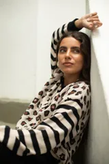 Saco de punto con diseño combinado de estampado animal print en el cuerpo y rayas horizontales en las mangas. Presenta cuello redondo, cierre frontal con botones y terminaciones en tejido acanalado negro.