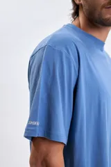 Remera de manga corta con corte oversize, color azul piedra, con estampa gráfica en la espalda que incluye el texto 'Miles Morales Spider-Man Brooklyn New York'.