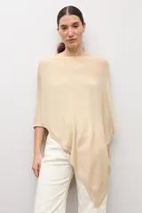 Capa tejida en hilo de lurex color beige, con cuello bote y diseño asimétrico de corte fluido.