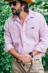 Camisa de manga larga color rosado, con cuello camisero, cierre frontal con botones de madera, dos bolsillos frontales en el pecho y etiqueta de marca aplicada.