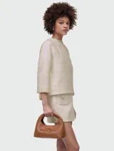 Cartera tipo hobo de Marc Jacobs, modelo The Mini Sac Bag, confeccionada en cuero color marrón, con diseño curvo, asa superior integrada y logo de la marca grabado en el frente.