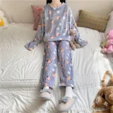 Conjunto de pijama de dos piezas confeccionado en plush suave, compuesto por una remera de manga larga y pantalón largo. Presenta un diseño estampado de duraznos sobre fondo color crema.