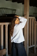 Camisa de lino de corte relajado y silueta holgada, con cuello clásico y cierre frontal de botones forrados en lino a rayas. Presenta mangas largas con puños amplios.