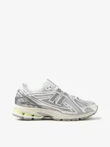 Championes urbanos New Balance modelo 1906R, con diseño técnico en tonos gris, blanco y detalles en verde lima. Presentan una estructura de malla transpirable con superposiciones sintéticas, logo N lateral y entresuela con tecnología de amortiguación.