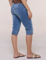 Pantalón capri de denim azul con cintura tipo faja elastizada, bolsillos frontales y traseros, y ajuste entallado por debajo de la rodilla.