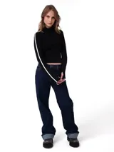 Remera de manga larga ajustada al cuerpo, color negro, con cuello alto y detalle de franja blanca lateral en las mangas. Incluye aberturas para el pulgar en los puños.