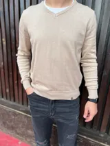 Buzo fino de algodón color beige con escote en V y mangas largas, de calce clásico y cómodo.