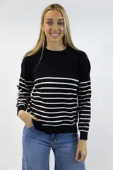 Buzo de tejido fino negro con diseño de rayas horizontales blancas en contraste. Presenta cuello redondo, mangas largas y terminaciones acanaladas en cuello, puños y cintura.