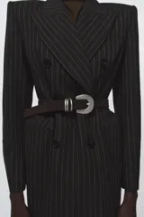 Cinturón de mujer marca Zara, confeccionado en piel de ante color marrón oscuro. Presenta una hebilla metálica ovalada de estilo rústico con un diseño distintivo de triple pasador metálico.