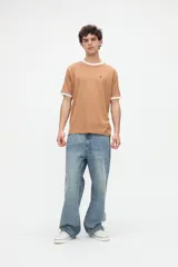 Remera de manga corta azul con cuello redondo, puños y bandas en los hombros en color tostado. Presenta un pequeño bordado rojo en el pecho y está confeccionada en suave jersey de algodón con calce clásico.