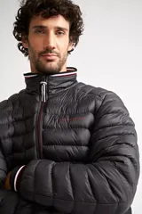 Campera puffer de nylon color azul marino, con cierre frontal completo, cuello alto y puños con detalle de rayas. Cuenta con bolsillos laterales con cierre y logo estampado en el pecho.