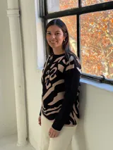 Sweater de tejido de punto con diseño estampado abstracto en tonos negro y beige, de cuello redondo y manga larga.