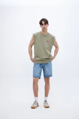 Musculosa verde oliva con cuello redondo y estampado pequeño en el pecho. Corte recto y sin mangas.