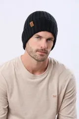 Gorro tejido de punto grueso con diseño acanalado y vuelta en el borde. Incluye una pequeña etiqueta de cuero sintético en el lateral.