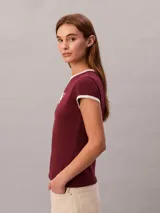 Remera Calvin Klein de color bordó, corte ajustado y manga corta. Presenta cuello redondo y ribetes en las mangas de color blanco en contraste, además de un estampado gráfico en el pecho con el nombre de la marca y el año 1968.