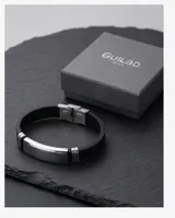 Pulsera de diseño moderno compuesta por una banda de goma negra y una placa central de acero inoxidable pulido.