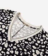 Blusa de crepé con estampa de manchas en blanco y negro, mangas cortas y escote en pico con borde contrastante.
