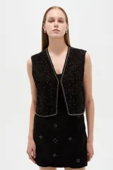 Chaleco negro de algodón sin mangas, con escote en V y bordados detallados.