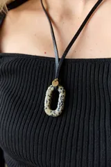 Collar con tiento negro y dije de piedra natural ovalada en tonos grises y azules.